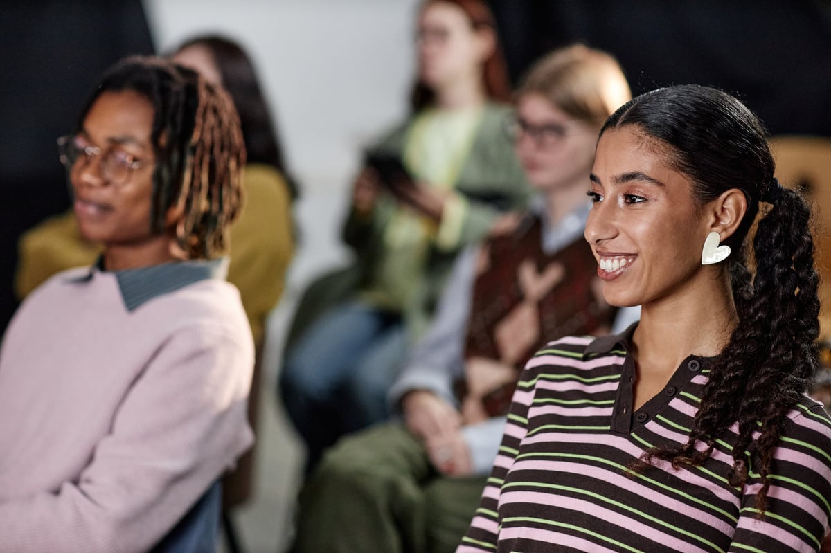 Diverse adults listening and smiling during a community wellness session in a bright room